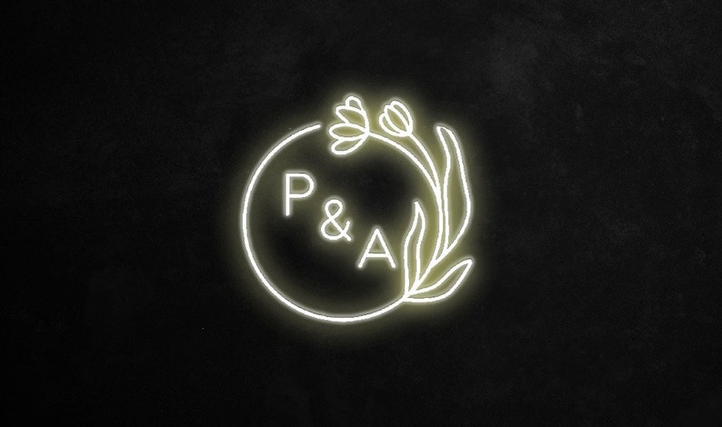 May include: A white neon sign with a circle and the letters "P & A" inside. The circle is surrounded by a stylized floral design.
