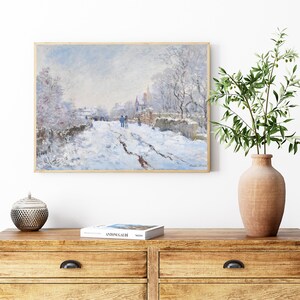 Pu&ograve; includere: Un dipinto che rappresenta una scena di strada innevata con persone che camminano in lontananza. Il dipinto &egrave; incorniciato in una cornice di legno chiaro e appeso a una parete bianca.