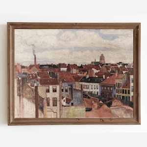 May include: An antique framed painting depicts a cityscape with red-tiled roofs, chimneys, and buildings in various colors. The sky is cloudy, and the artwork has a vintage aesthetic. The painting is in a brown wooden frame.
