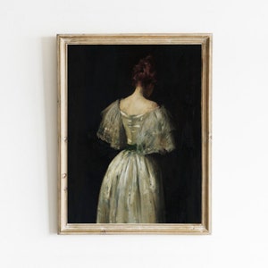 May include: A framed oil painting of a woman in a white dress with a green sash. The woman is standing with her back to the viewer and her head is turned to the side. The painting is set against a dark background.