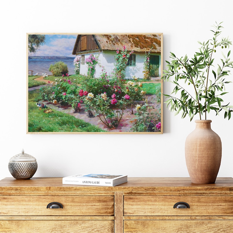 Puede incluir: Una pintura de una caba&ntilde;a blanca con techo de paja rodeada de un jard&iacute;n de rosas rosas y blancas. La caba&ntilde;a tiene una puerta y ventanas verdes. El jard&iacute;n es exuberante y verde con un camino que lleva a la caba&ntilde;a.