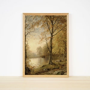 以下が含まれることがあります： 秋らしい穏やかな風景を描いた額装された絵画。絵画には、金色に輝く葉をつけた木々に囲まれた湖が描かれており、暖かく居心地の良い雰囲気を作り出しています。