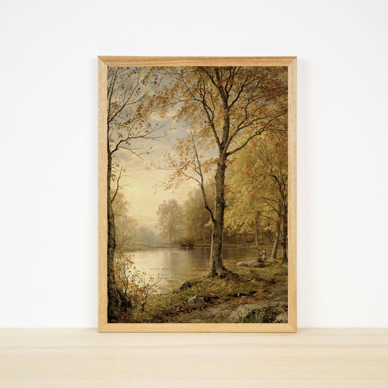 以下が含まれることがあります： 秋らしい穏やかな風景を描いた額装された絵画。絵画には、金色に輝く葉をつけた木々に囲まれた湖が描かれており、暖かく居心地の良い雰囲気を作り出しています。
