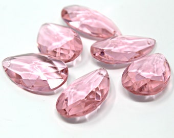 May include: Six faceted, teardrop-shaped beads in a pale pink colour. Each bead has a hole for threading. The beads are arranged on a white surface, highlighting their light-catching facets and delicate form.