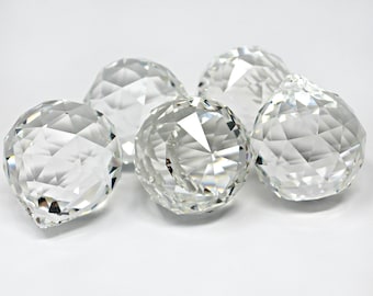 May include: Five clear crystal ball ornaments with faceted surfaces. The ornaments are arranged in a cluster on a white background.