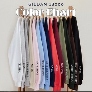 May include: A color chart of Gildan 18000 sweatshirts in various colors, including white, ash, sports grey, sand, light pink, light blue, carolina blue, navy, red, maroon, military green, forest green, dark chocolate, and black. The text "Color Chart" is at the top.