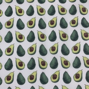 May include: White fabric with a repeating pattern of green avocado halves. The avocados are arranged in rows and columns.
