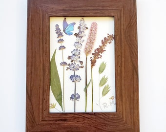 Pressed dried wild flowers lavender with a cute blue butterfly sticker in a wood like frame, for home décor or as a gift