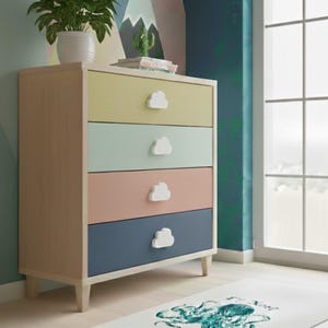 May include: A four-drawer chest of drawers with pastel-coloured drawers and cloud-shaped knobs. The drawers are yellow, mint green, pink, and navy blue. The chest is made of light wood and sits on short legs. A white rug with a teal octopus design is on the floor.