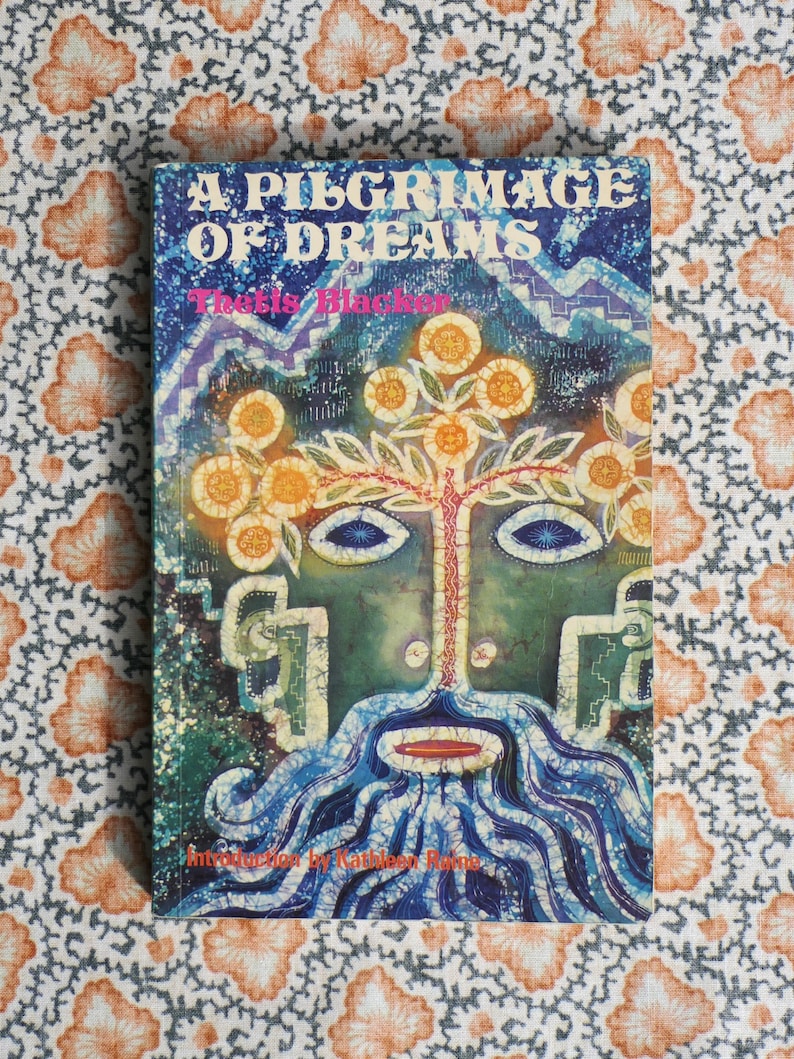 K&ouml;nnte beinhalten: Ein Vintage-Buch mit dem Titel "A Pilgrimage of Dreams" mit einem farbenfrohen, abstrakten Cover-Design. Das Cover zeigt ein gesichts&auml;hnliches Bild mit einem Baum und floralen Elementen in Blau-, Gr&uuml;n- und Gelbt&ouml;nen. Das Buch liegt auf einem gemusterten Stoff.