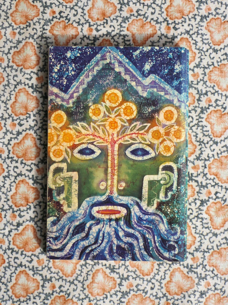 K&ouml;nnte beinhalten: Ein Hardcover-Buch mit einer lebendigen, abstrakten Illustration. Das Cover zeigt ein gesichts&auml;hnliches Design mit einer baumartigen Struktur, einem blauen Bart und einer Bergkette oben. Die Farbpalette umfasst Blau-, Gr&uuml;n- und Oranget&ouml;ne.