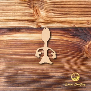 May include: Wooden cutout of a character from the movie Toy Story. The character is made to look like a spoon with arms and legs. The cutout is on a brown wooden background.