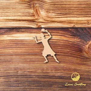 May include: A cutout silhouette of a person in a hat and dress, holding a ball, on a wood background. The silhouette is made of brown paper.