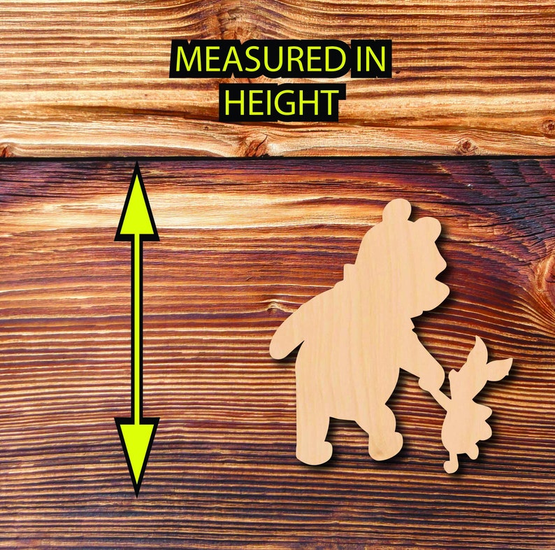 May include: Wooden cutout of Winnie the Pooh and Piglet holding hands. The cutout is on a brown wood background.  MEASURED IN HEIGHT is written above the cutout.