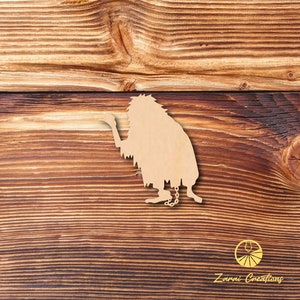 May include: A wooden cutout of a hairy, chained creature with a raised hand, against a woodgrain background. The cutout is light brown and the background is a darker brown.