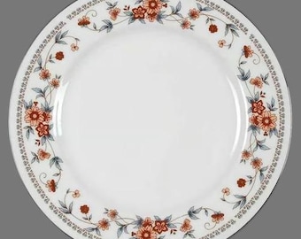 May include: White ceramic dinner plate with a floral border design. The border features a repeating pattern of red, orange, and brown flowers with green leaves on a white background.