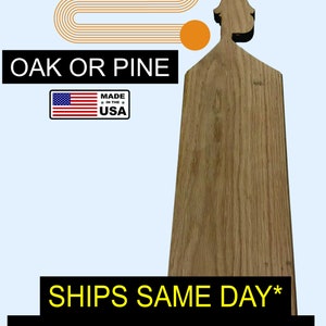 Op de afbeelding: Een houten snijplank met een decoratief bovenstuk in de vorm van een vrouwenhoofd. De plank is gemaakt van eikenhout of dennenhout en is gemaakt in de VS. De tekst "SHIPS SAME DAY* 100% SHIPPED FROM USA ORLANDO, FL" staat gedrukt op de onderkant van de plank.