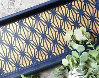 May include: A navy blue wooden tray with a gold geometric pattern. The tray is decorated with a stencil design and has a modern, minimalist aesthetic.