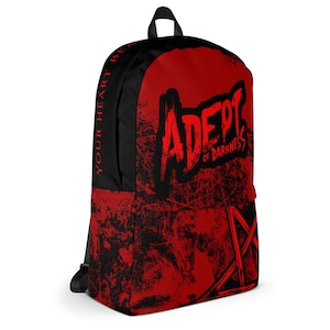 Könnte beinhalten: Ein schwarz-roter Rucksack mit einem abgenutzten Texturmuster. Die Vorderseite zeigt den Text ADEPT OF DARKNESS in einer gezackten Schrift über einer Pentagramm-Grafik. Das Seitenteil enthält den vertikalen Text YOUR HEART BEATS.