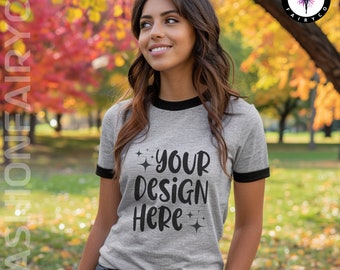 May include: A gray and black ringer t-shirt with the text "YOUR DESIGN HERE" in black. The shirt is being modeled by a person in a park setting.