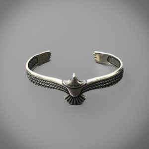 Op de afbeelding: Een zilveren armband met een adelaar ontwerp. De adelaar is in vlucht met zijn vleugels uitgespreid. De armband is gemaakt van metaal en heeft een gladde afwerking.