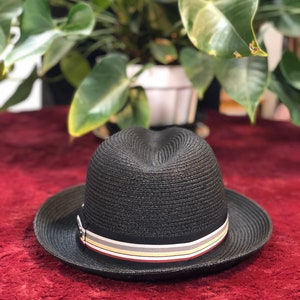 Pode incluir: Um chapéu de palha preto de aba larga com uma faixa de listras multicoloridas.