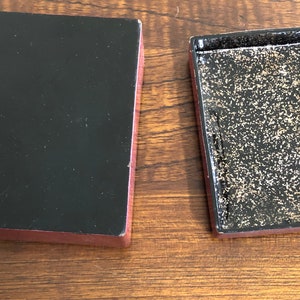 May include: A red wooden box with a black interior. The box is open and the inside is lined with gold glitter.