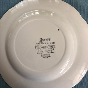 May include: White ceramic plate with a scalloped edge. The back of the plate has a black and white logo that reads "ASCOT SERVICE PLATE by WOOD & SONS ENGLAND DECORATIVE WALL PLATE NOT A DINNERWARE PATTERN".