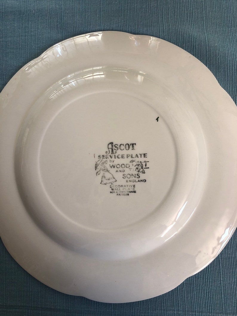 May include: White ceramic plate with a scalloped edge. The back of the plate has a black and white logo that reads "ASCOT SERVICE PLATE by WOOD & SONS ENGLAND DECORATIVE WALL PLATE NOT A DINNERWARE PATTERN".