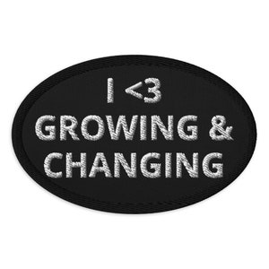 Könnte beinhalten: Schwarzer, ovaler gestickter Aufnäher mit weißem Text, der "I <3 GROWING & CHANGING" lautet.