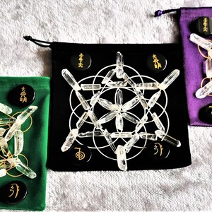 May include: Three velvet pouches with drawstring closures, each containing a set of clear quartz crystal points arranged in a geometric pattern. The pouches are green, black, and purple. Each pouch has black circular stones with gold lettering.