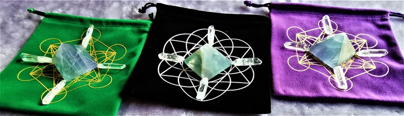 May include: Three velvet pouches with a green, black, and purple exterior. Each pouch contains a clear crystal pyramid and four clear quartz points arranged in a star pattern.