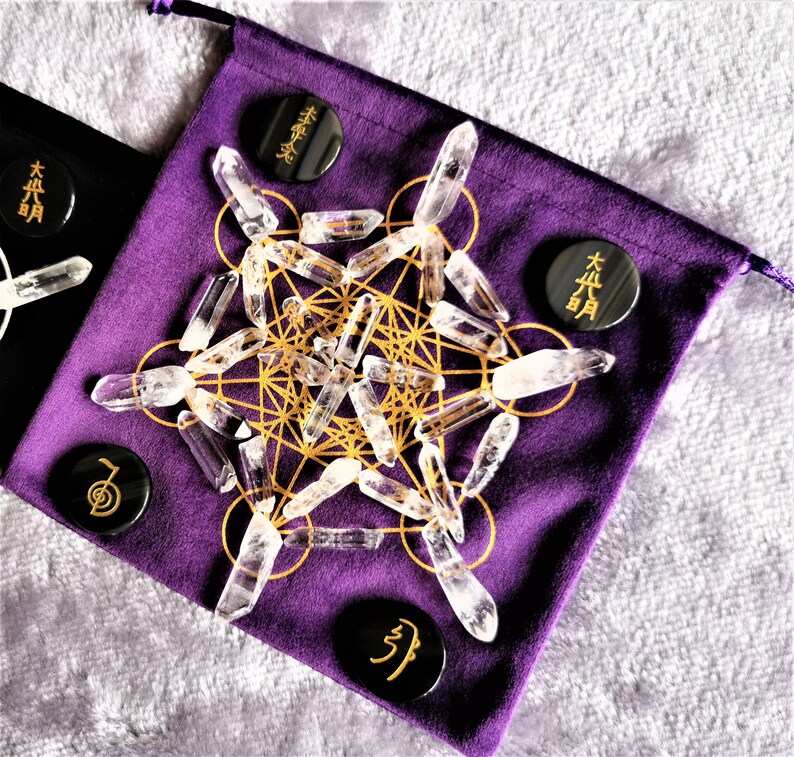 May include: A purple velvet pouch with a gold geometric pattern and clear quartz crystals. There are four black circular stones with Japanese characters on them.