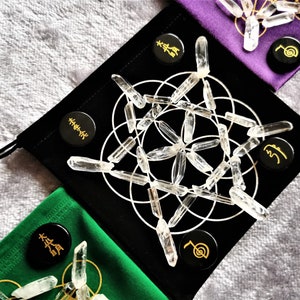 May include: A black velvet pouch with a white geometric pattern and clear quartz crystals. The pouch has three black circular tokens with gold lettering and symbols.