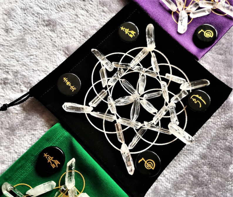 May include: A black velvet pouch with a white geometric pattern and clear quartz crystals. The pouch has three black circular tokens with gold lettering and symbols.