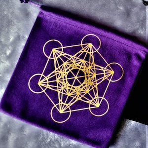 May include: Purple velvet pouch with a gold geometric design, resembling a star with circles around it.