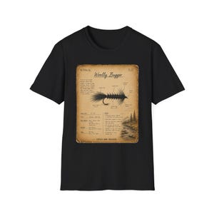 May include: A black short-sleeve t-shirt featuring a rectangular graphic on the chest. The graphic is a vintage-style tan document titled Woolly Bugger, displaying a detailed illustration of a fishing fly with labels and descriptive text.