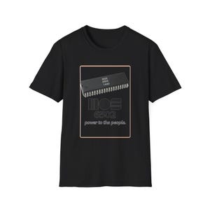 May include: Black t-shirt featuring a graphic of a MOS 6502 integrated circuit with the text "MOS 6502 power to the people." The design is enclosed in a rectangular frame.