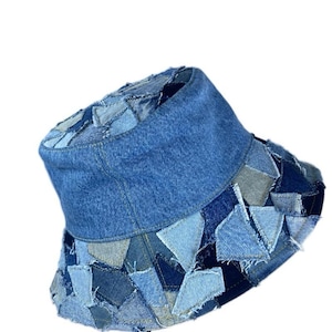 Könnte beinhalten: Ein blauer Jeans-Bucket-Hut aus Patchwork-Stücken aus Jeans. Der Hut hat eine breite Krempe und eine flache Krone.
