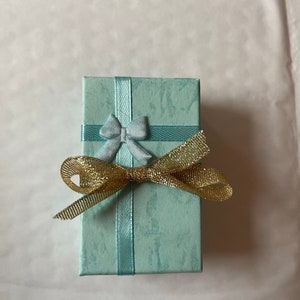 May include: A small, light blue gift box with a blue bow and a gold ribbon.