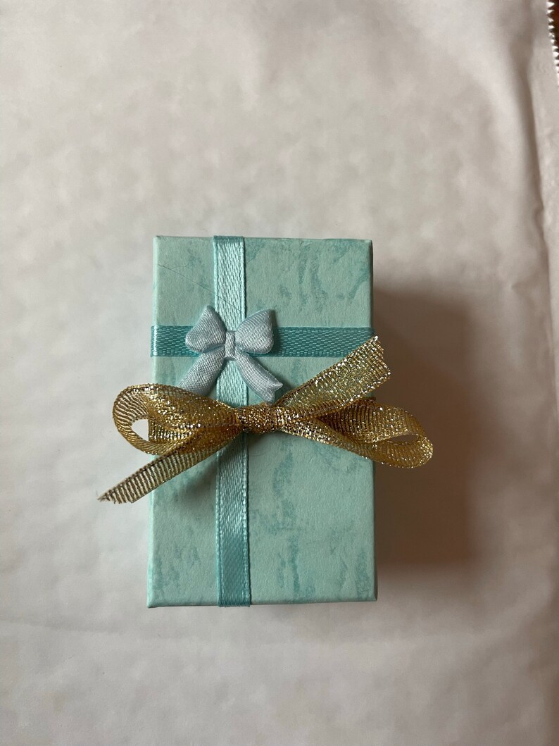 May include: A small, light blue gift box with a blue bow and a gold ribbon.