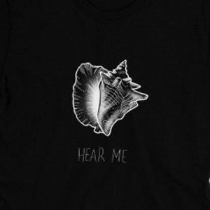 Puede incluir: Camiseta negra con una ilustración blanca de una concha y el texto "Hear Me" impreso en la parte delantera.
