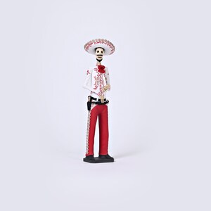 Op de afbeelding: Een wit skeletfiguur dat een rood-wit geborduurd pak draagt, een zwarte riem en een brede sombrero met rode en gouden versieringen. Het figuur staat op een zwarte basis.