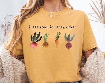 May include: A yellow t-shirt with the text "Lets root for each other" and a watercolor illustration of five different vegetables.