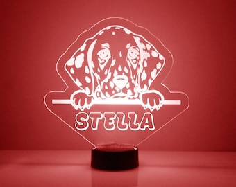 May include: White LED night light featuring a Dalmatian dog peering over the top. The light has a clear acrylic base and a black base. The name "STELLA" is written below the dog.