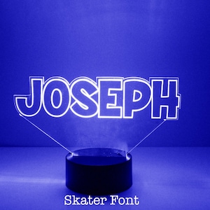 May include: A white LED night light with the name "JOSEPH" in a bold, stylized font. The light is on a black base and the text "Skater Font" is below the base.