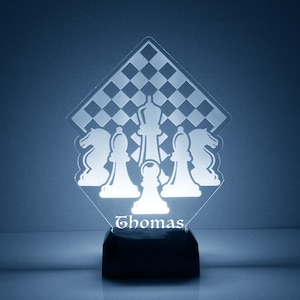 May include: A white acrylic night light shaped like a diamond with a chessboard pattern and chess pieces. The name "Thomas" is engraved on the base of the light.