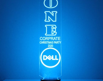 May include: A clear acrylic plaque with the word "ONE" in large white letters, followed by the text "CORPORATE CHRISTMAS PARTY 2020". The Dell logo is at the bottom of the plaque.