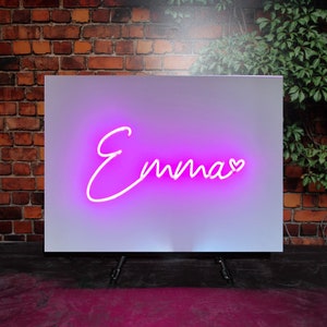Op de afbeelding: Een wit bord met een roze neon-bord met de tekst "Emma" met een klein hartje na de naam.