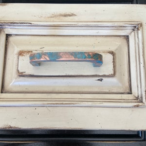 May include: A white drawer with a distressed finish and a copper drawer pull with a turquoise patina.